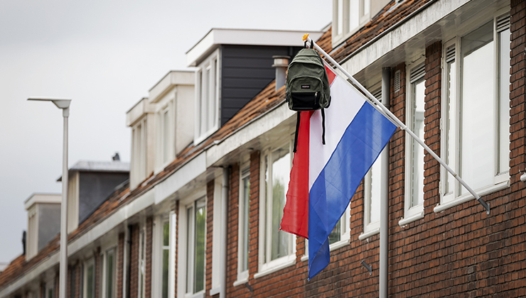 Een huis met een Nederlandse vlag en schooltas hier is iemand geslaagd
